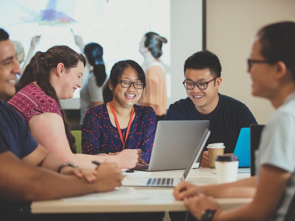 People working together gathered around laptop