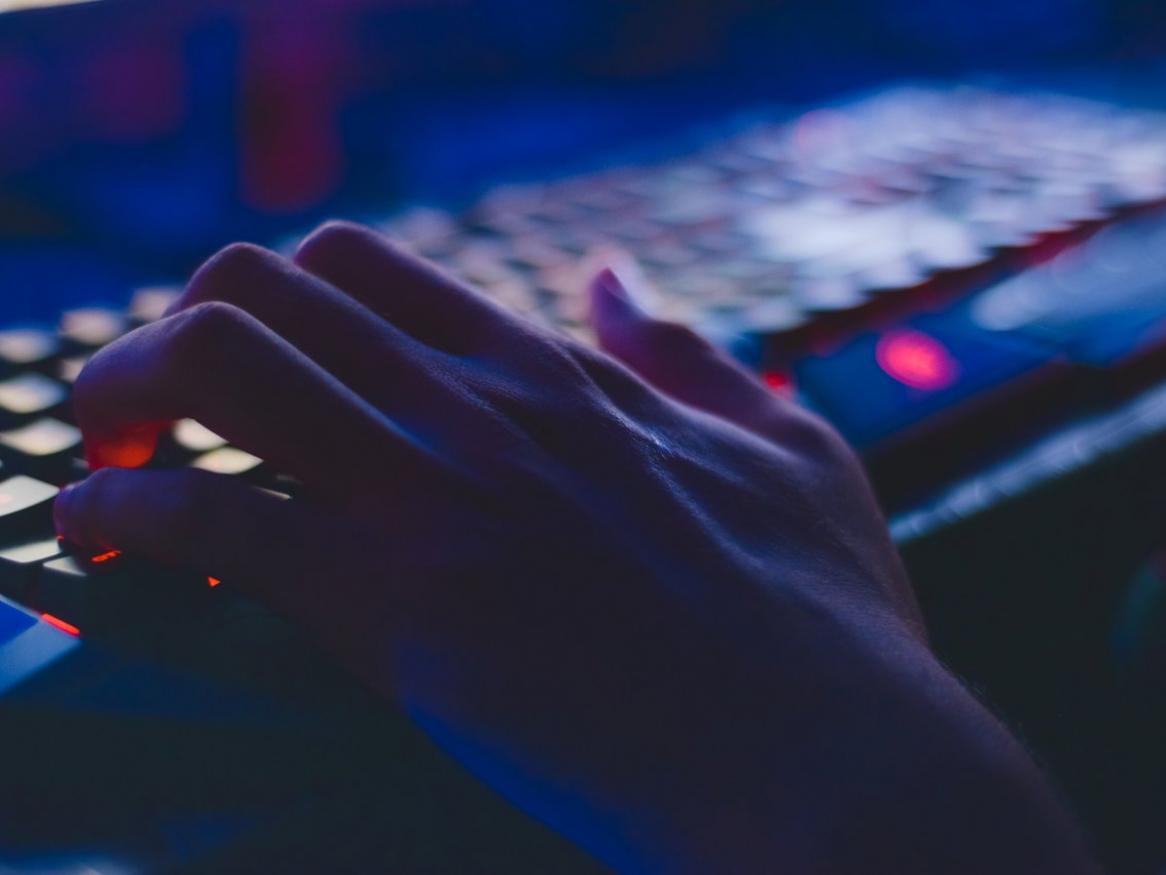 Close up photo of a hand on a keyboard in low light