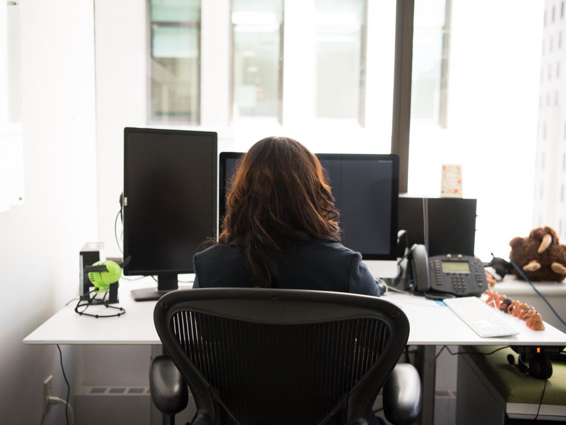 A woman sits working at her desk