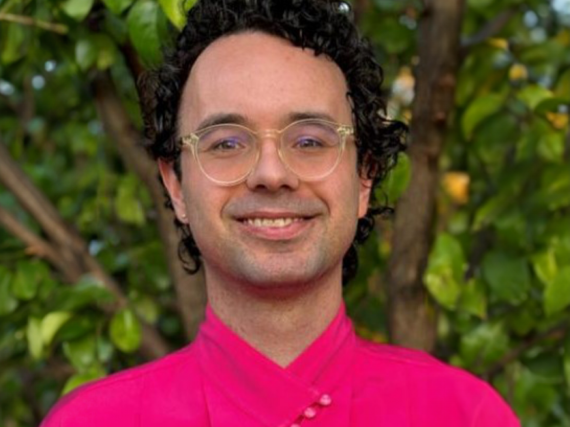 A portrait of Joshua in a bright pink shirt